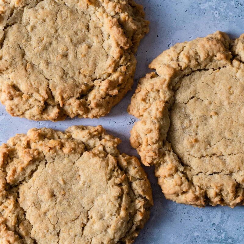 These homestyle Coconut Cookies from Grandma's Cookies feature a golden-brown color and a hearty, chewy texture. The cookies are generously studded with shredded coconut bits that add a satisfying crunch and tropical flavor to the classic cookie.